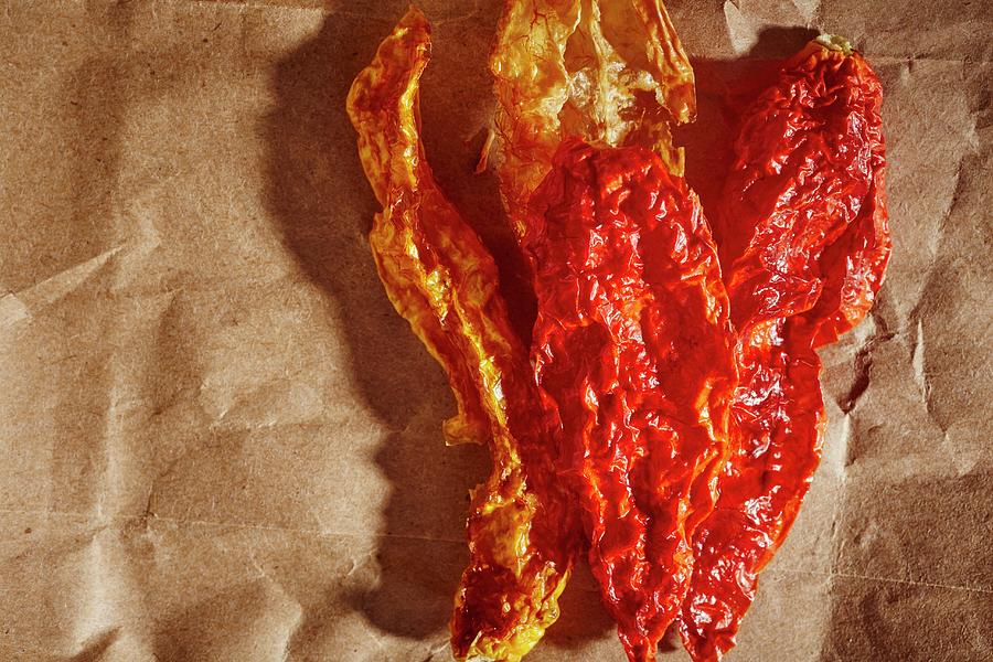 Dried Chilli Peppers On A Piece Of Brown Paper Photograph by Brian Yarvin
