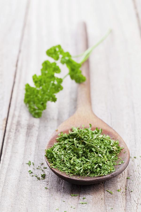 Dried Parsley On A Wooden Spoon With A Sprig Of Fresh Parsley Photograph by Shawn Hempel