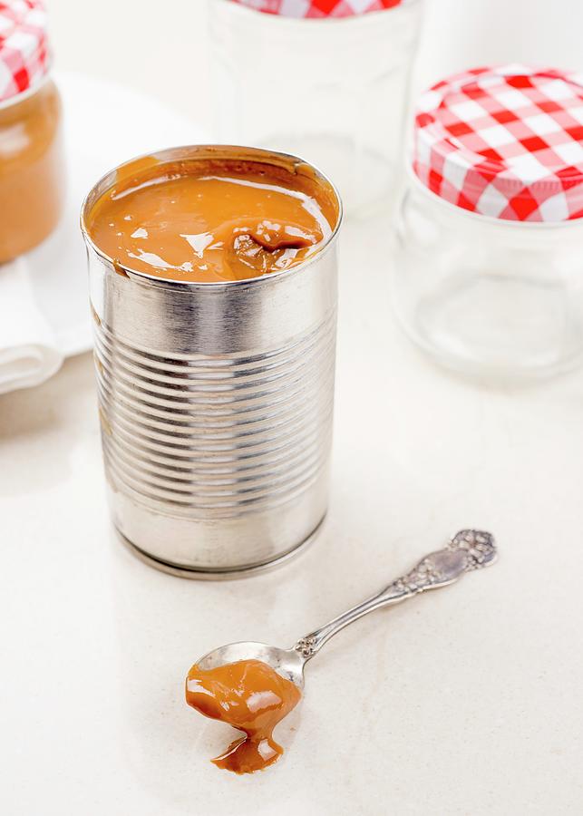 Dulce De Leche In A Tin And On A Spoon Photograph by Clara Gonzalez