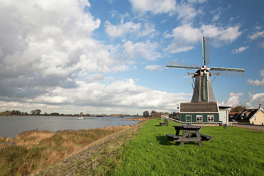 Dutch Windmill On Bank Of River Photograph by Roel Meijer