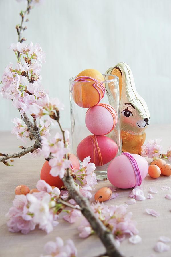 Easter Arrangement Of Dyed Eggs, Chocolate Rabbit & Sprig Of Cherry Blossom Photograph by Martina Schindler