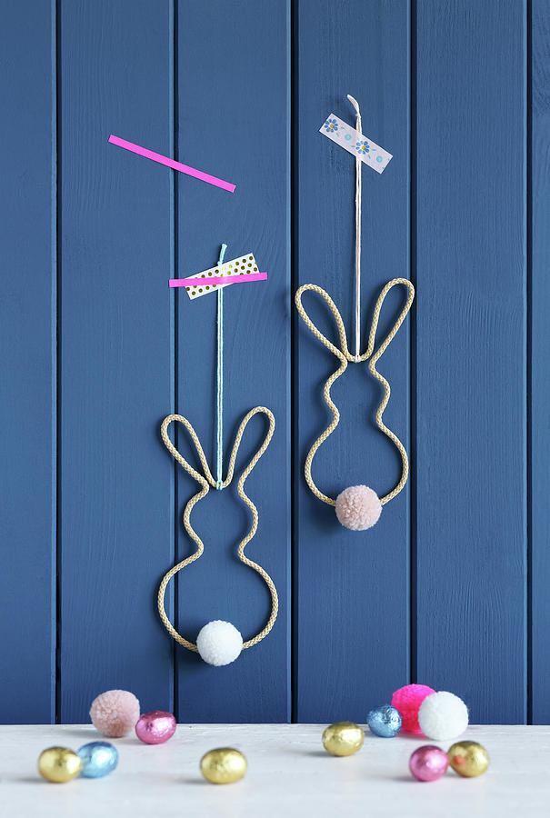 Easter Bunnies Made From Knitted Tubes, Wire And Pompoms On Wall Photograph by Thordis Rggeberg