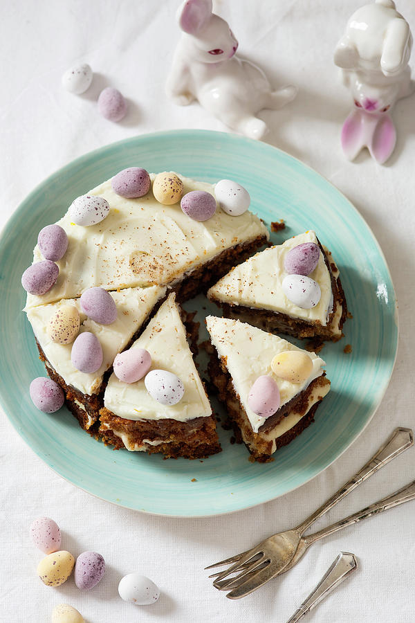 Easter Carrot Cake Decorated With Mini Eggs And Nutmeg With Bunnies In The Background Photograph by Stacy Grant