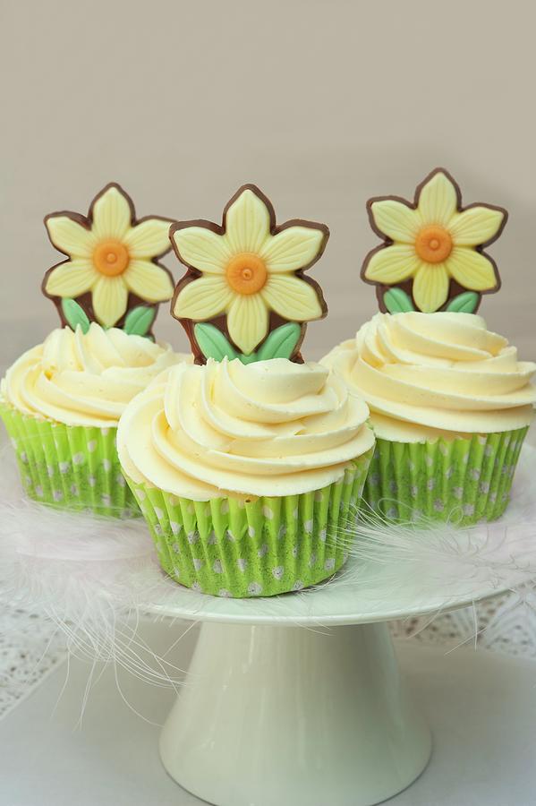 Easter Cupcakes On A White Cake Stand, Decorated With Feathers And Chocolate Spring Daffodil Flowers On White Lace Photograph by Linda Burgess