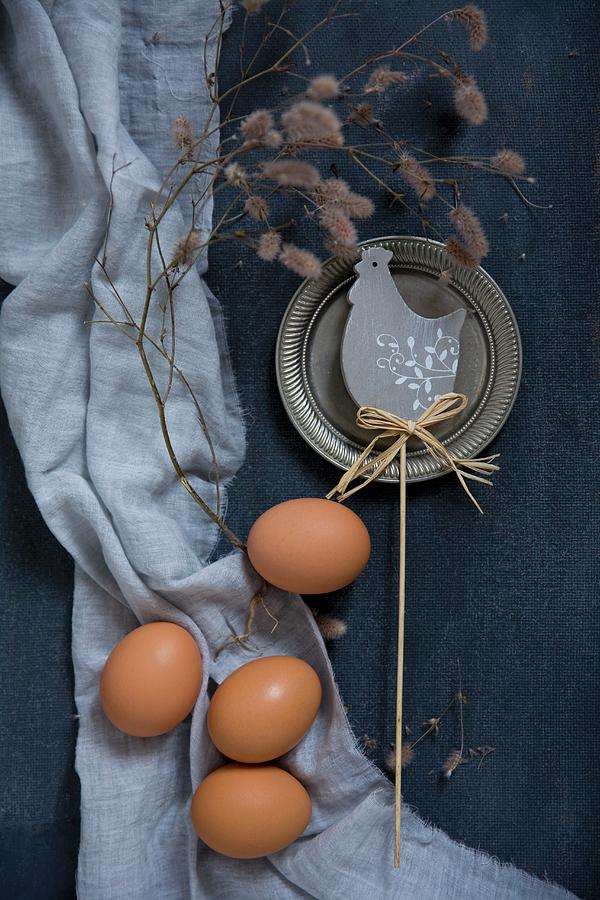 Easter Decorations With Chicken Eggs And A Branch Beside A Chicken Motif On A Blue Background Photograph by Alicja Koll