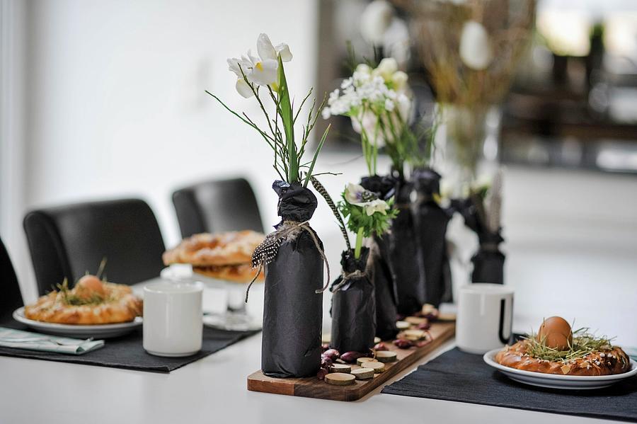 Easter Dining Table Set In White With Bottles Wrapped In Black Paper Used As Vases And Black Place Mats Photograph by Alexandra Feitsch