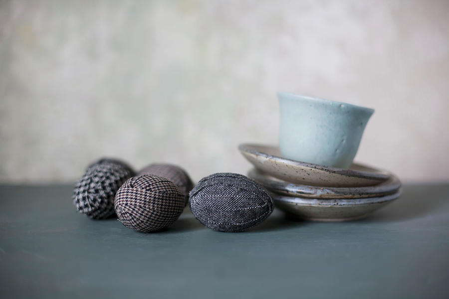 Easter Eggs Wrapped In Fabric Next To Cup On Stack Of Saucers Photograph by Alicja Koll