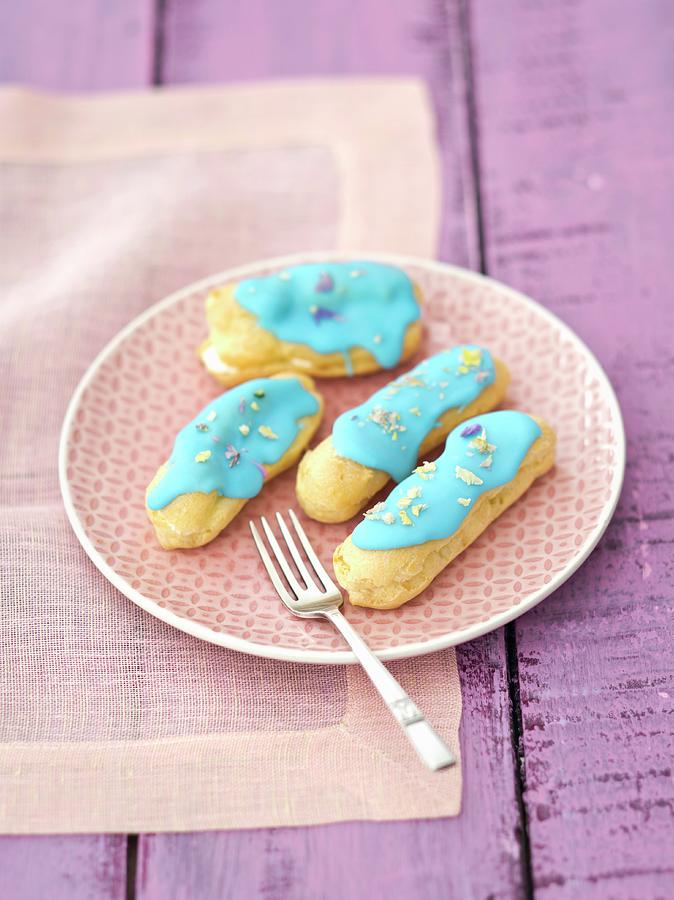 Eclairs With Blue Icing And Dried Pansy Petals Photograph by Rua Castilho