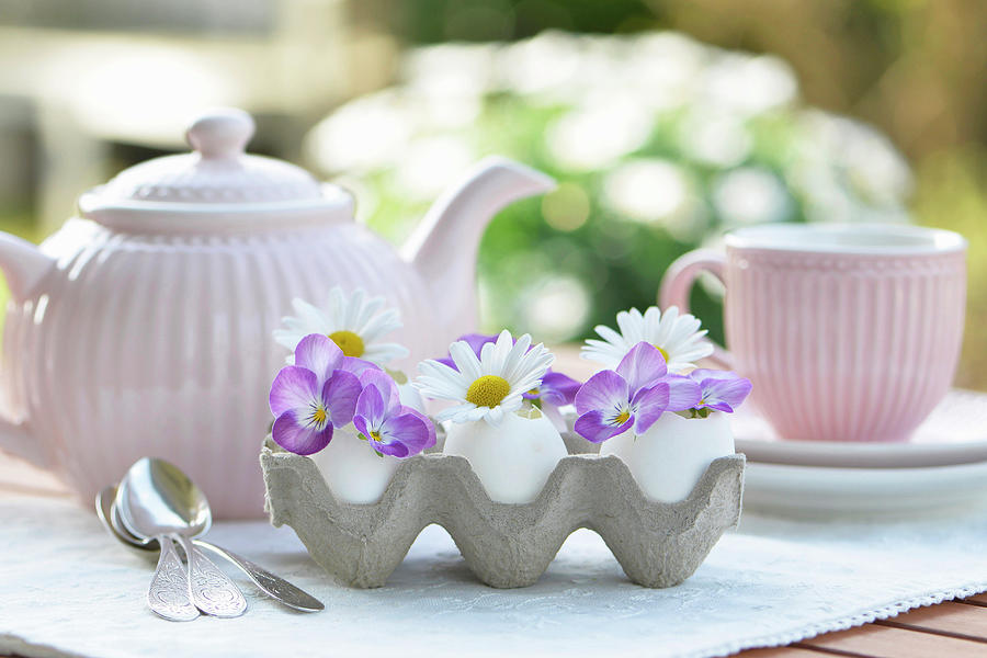 Egg As A Vase With Horned Violets And Marguerite Daisies, Behind It A Tea Setting Photograph by Daniela Behr