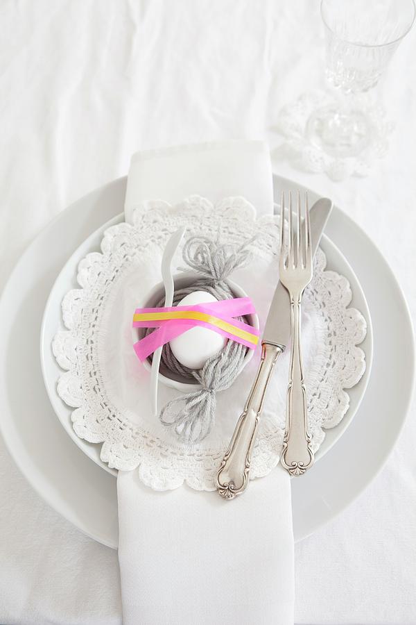 Egg In Nest Of Woollen Yarn On Easter Place Setting Photograph by Nikky Maier
