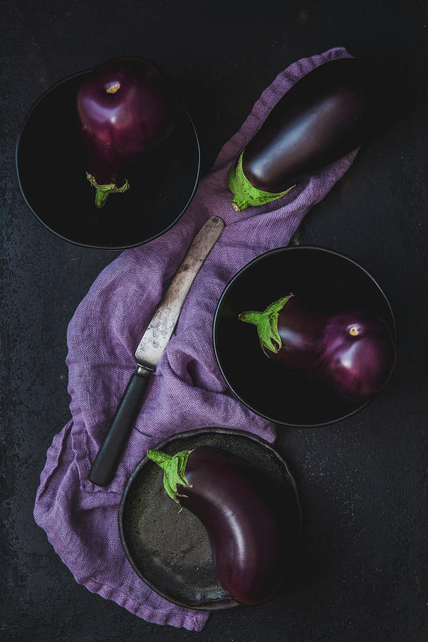 Eggplants On Dark Plates And Purple Linen Tea Towel Photograph by Aleksandra Kordalska