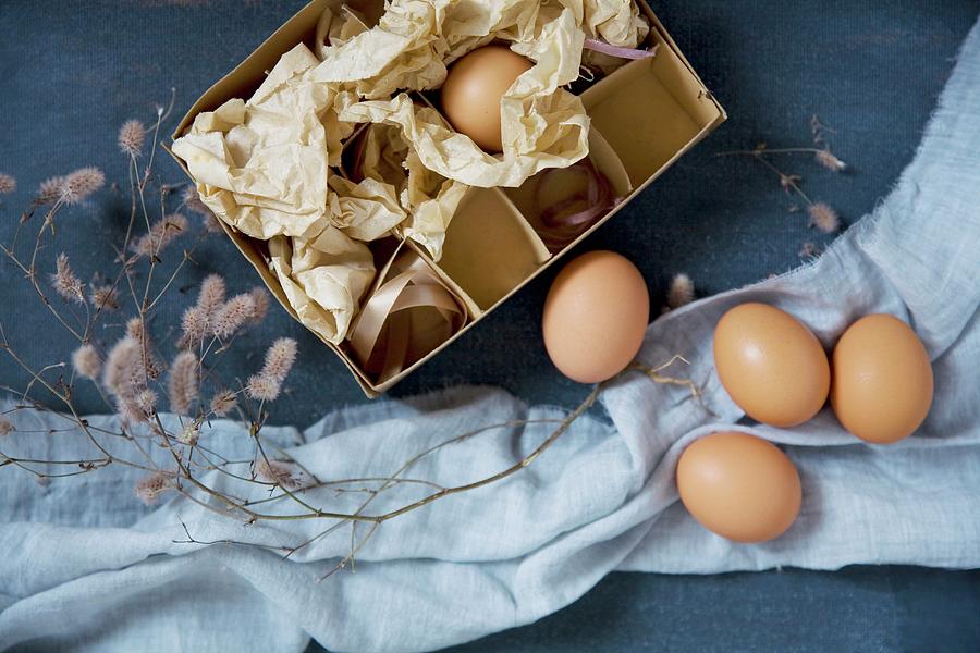 Eggs And Cardboard Box On Blue Surface Photograph by Alicja Koll