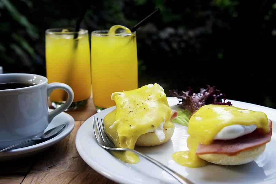 Eggs Benedict With Ham Served With Coffee And Juice On A Table Outside Photograph by Martina Schindler