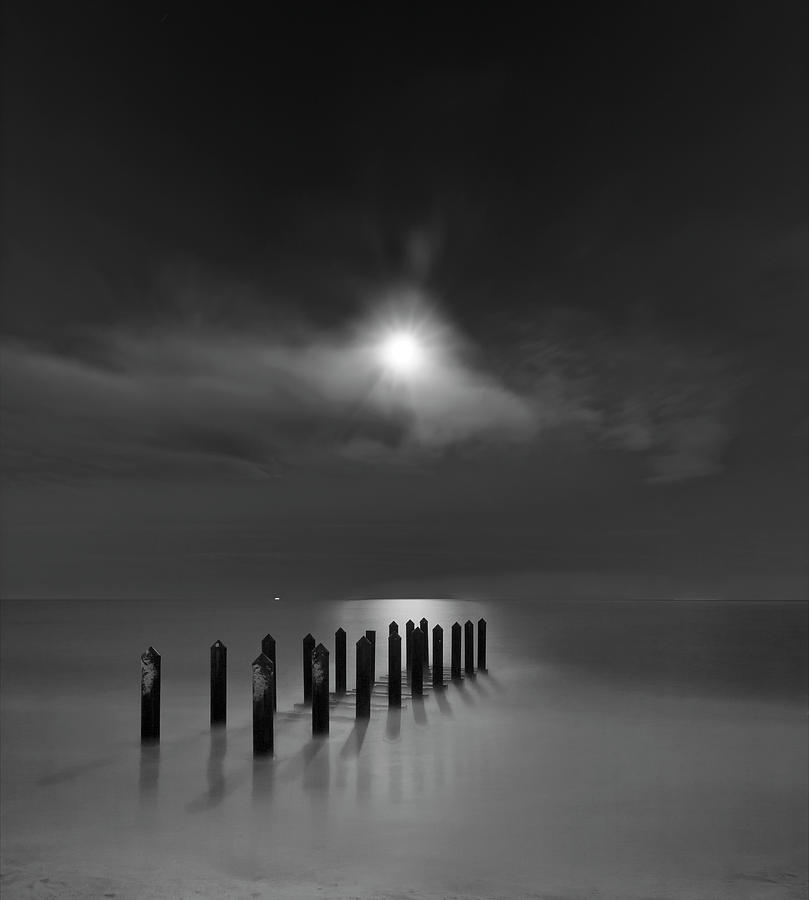 Black And White Photograph - Eighteen Pilings Beneath The Rising Moon by Geoffrey Ansel Agrons