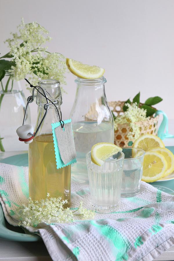 Elderflower Blossom Syrup In A Bottle And Poured Into Glasses With Lemon Slices Photograph by Regina Hippel