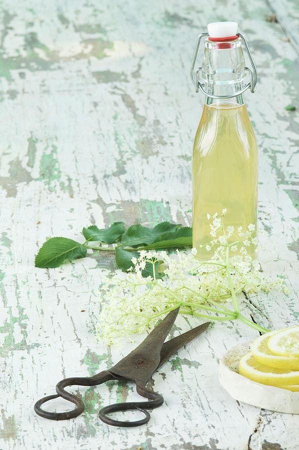 Elderflower Syrup, Elderflowers, Lemon Slices And A Pair Of Scissors On A Wooden Table Photograph by Achim Sass