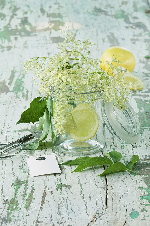 Elderflowers And Lemon Slices In A Glass On A Wooden Table Photograph by Achim Sass