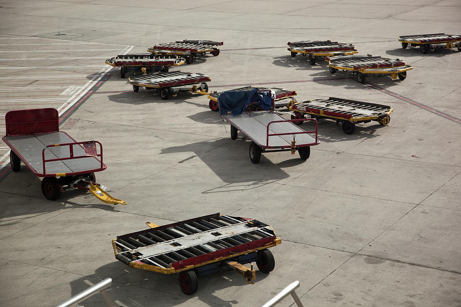 Empty Baggage Trailers On An Airport Photograph by Tobias Titz