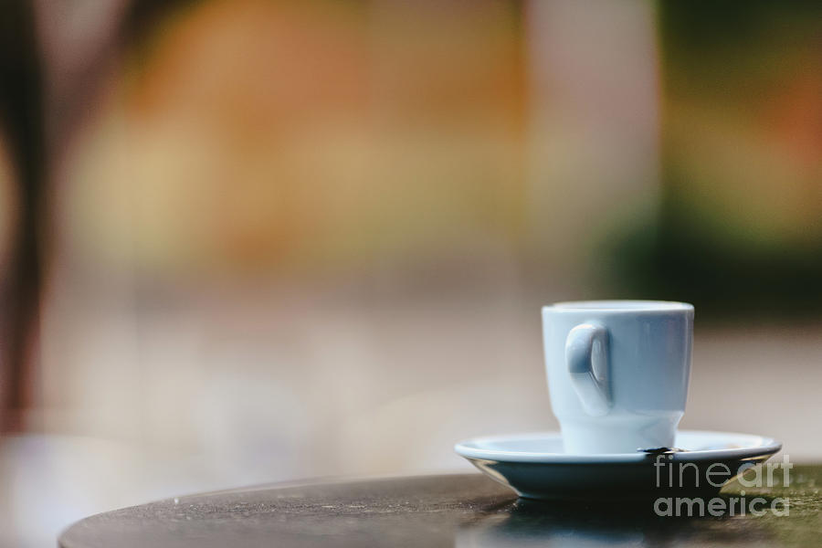Empty white coffee cup on the wooden table of an outdoor bar, negative space for text. Photograph by Joaquin Corbalan