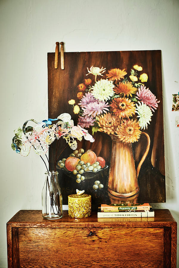 Fabric Flowers In Glass Bottle In Front Of Still-life Painting Of Flowers On Top Of Cabinet Photograph by Catherine Gratwicke