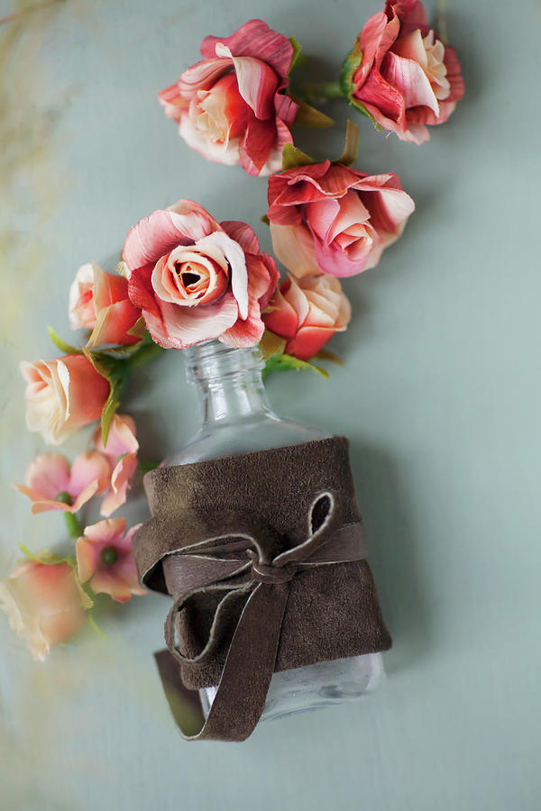 Fabric Roses And Bottle Tied With Leather Bow On Grey Surface Photograph by Alicja Koll
