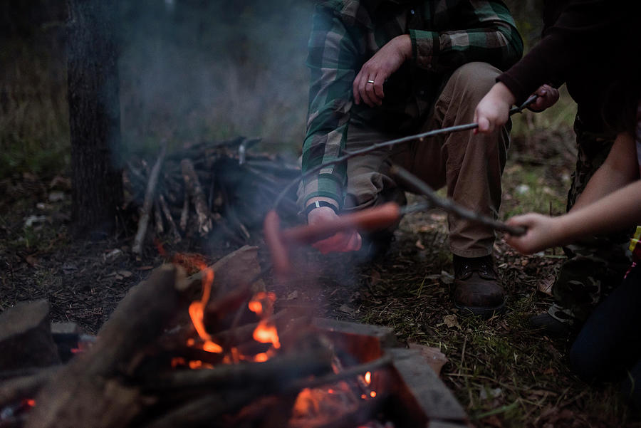 Meat Photograph - Family Roasting Sausages On Stick Over Campfire In Forest by Cavan Images