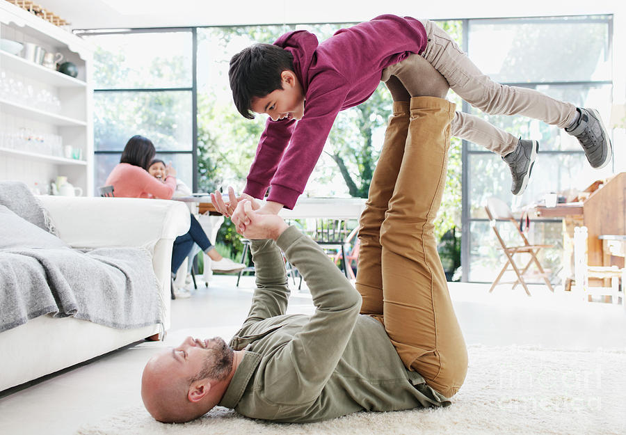 Father Lifting Son With Legs On Living Room Floor Photograph by Caia ...