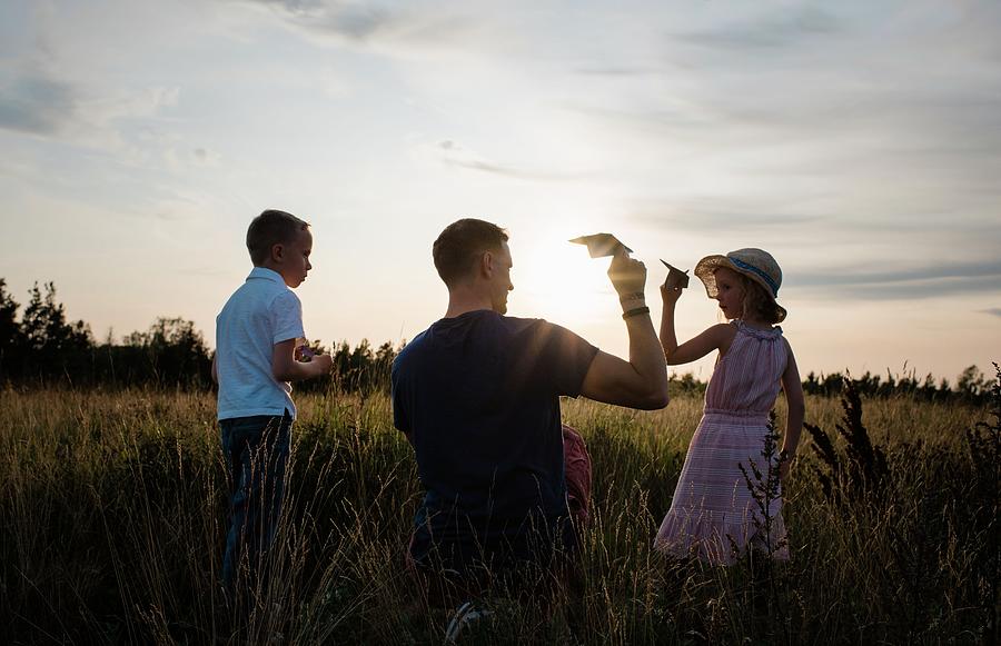 Parenthood Movie Photograph - Father Playing With Paper Aeroplanes With Son And Daughter At Sunset by Cavan Images