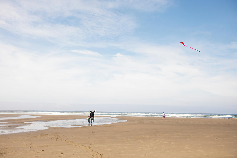 Dragon Photograph - Father Teaching Son How To Fly A Kite At The Beach. by Cavan Images