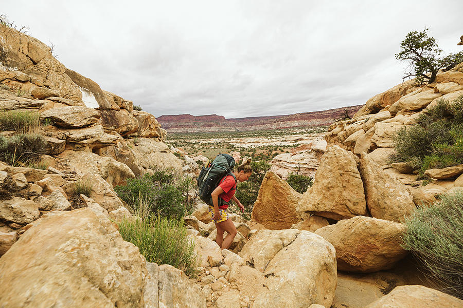 National Parks Photograph - Female Backpacker Hikes Over Rocky Rugged Terrain In Utah Desert by Cavan Images