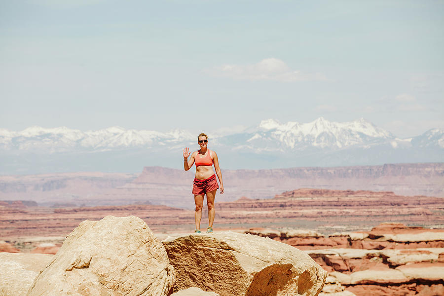 Female Hiker In Sports Bra And Shorts Waves From A Desert