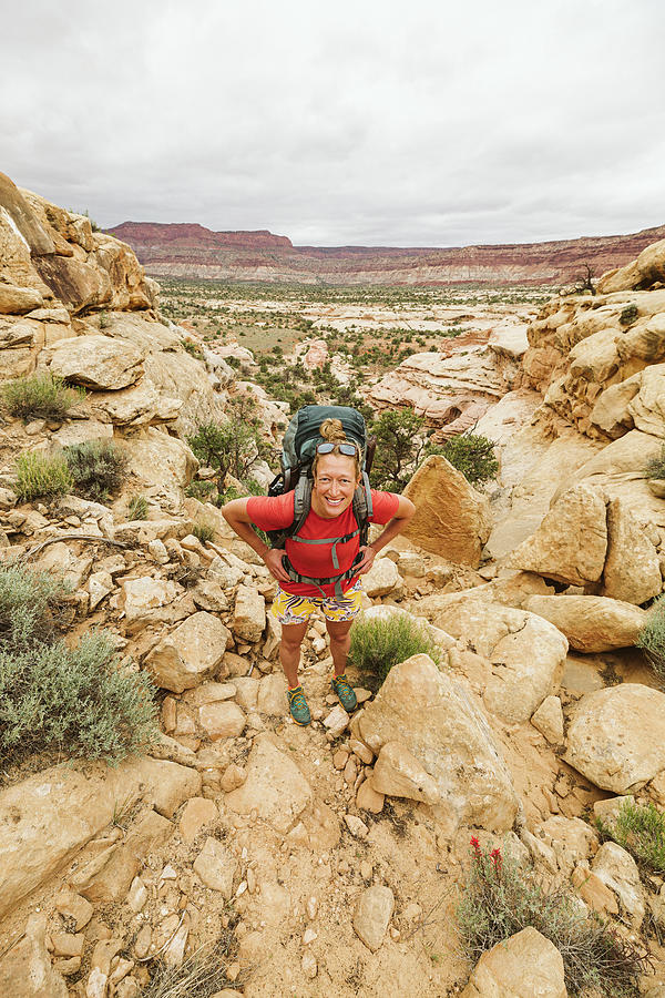Desert Photograph - Female Hiker With Hands On Hips Looks At Camera While Hiking Utah by Cavan Images