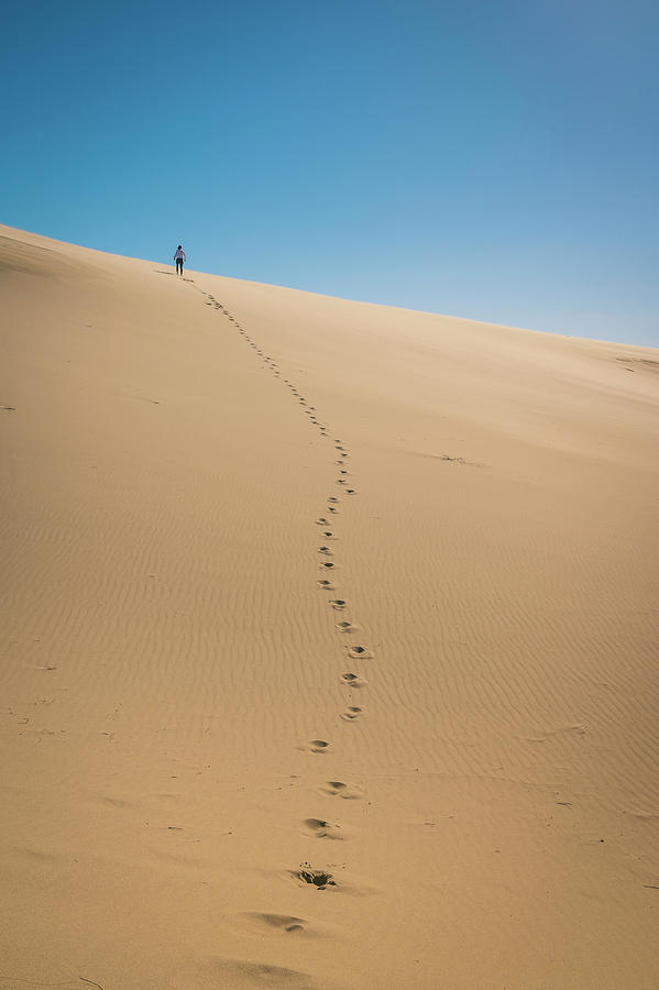 Female Standing On A Sand Dune With Line Of Footprints Photograph by ...