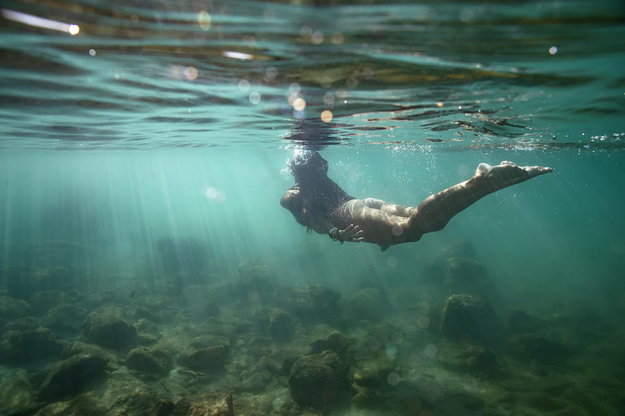 Female Swimming Away From Camera And Up To Surface Of Shallow Ocean 