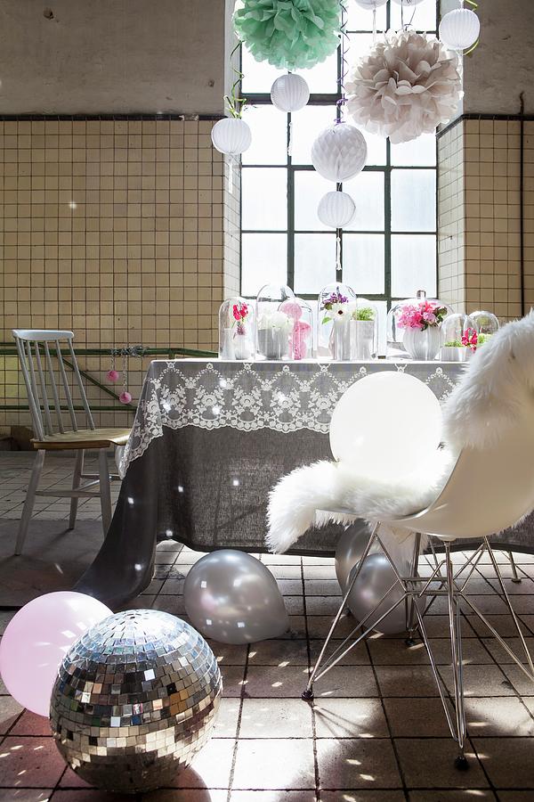 Feminine, Romantic Party Decorations With Light Reflecting From Disco Ball, Suspended Pompons And Flowers On Table In Disused Factory With Industrial Windows Photograph by Nikky Maier