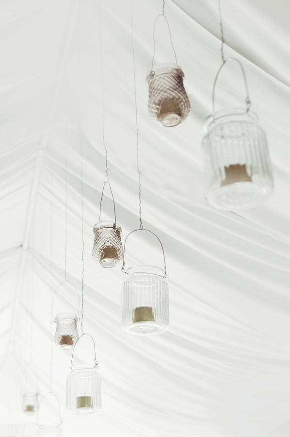 Festive Arrangement Of Candle Lanterns Hung From White Tent Ceiling For Wedding Photograph by Annette Nordstrom