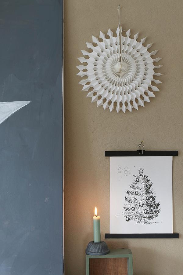 Festive Arrangement Of Picture, Paper Sunburst And Lit Candle Against Wall Photograph by Regina Hippel