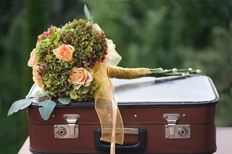 Festive Bouquet Of Apricot Roses And Hydrangeas Tied With Ribbon On Top Of Vintage Suitcase Photograph by Alicja Koll
