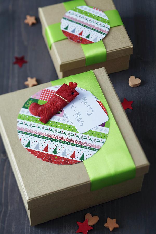 Festive Gift Boxes Decorated With Round Patterned Cards, Green Ribbons And Father Christmas Boot Photograph by Franziska Taube