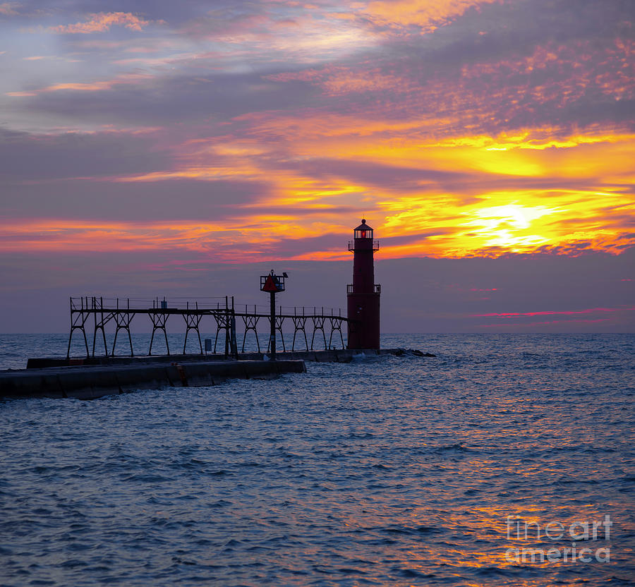 Fiery sunrise over lake with scenic lighthouse and rough waters ...