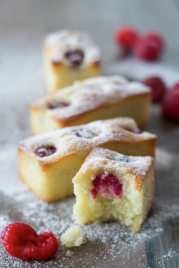 Financiers With Raspberries And Icing Sugar, One With A Bite Taken Out Photograph by Jan Wischnewski