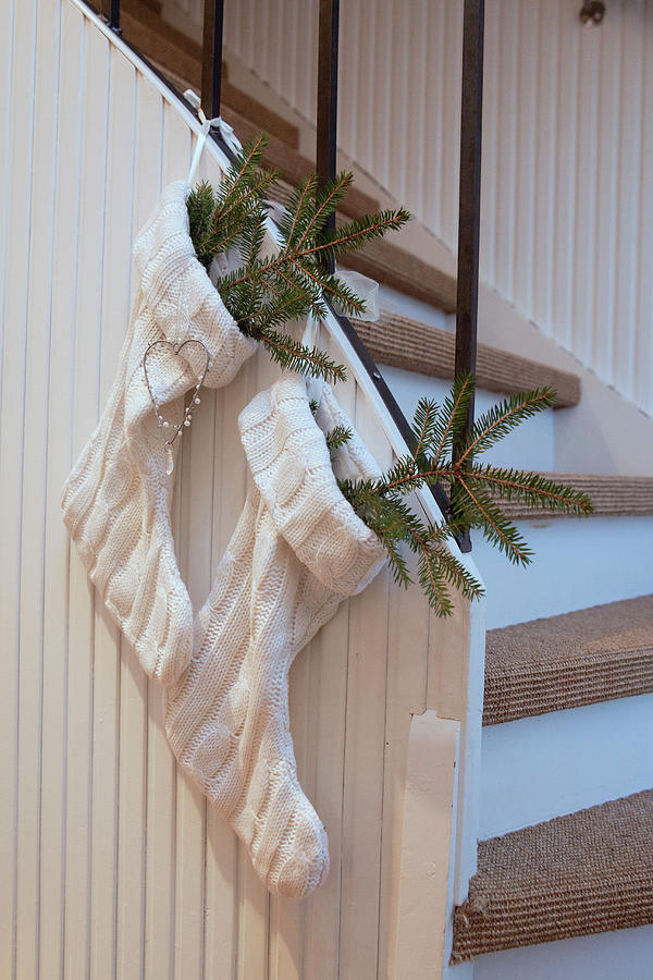 Fir Branches In Two White Knitted Christmas Stockings Hung From Stairs Photograph by Camilla Isaksson