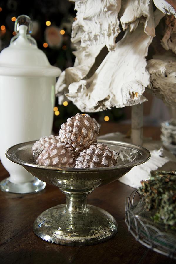 Fir Cone Baubles In Silver Footed Dish And White Glass Vessel With Lid On Table Photograph by Winfried Heinze