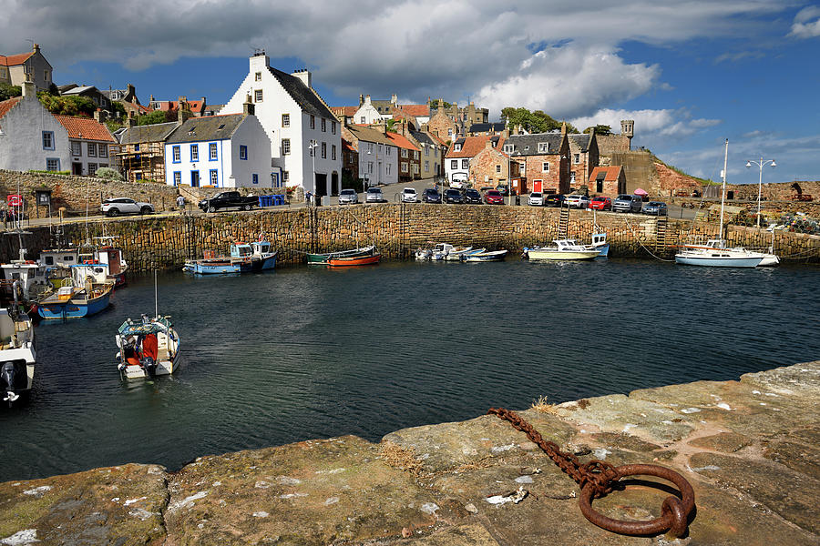 Fisherman on boat returning to Crail Harbour with stone piers an ...