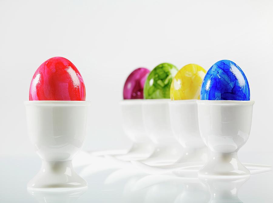 Five Eggs, Brightly Coloured For Easter, In White Eggcups With Egg Spoons Photograph by Foto4food