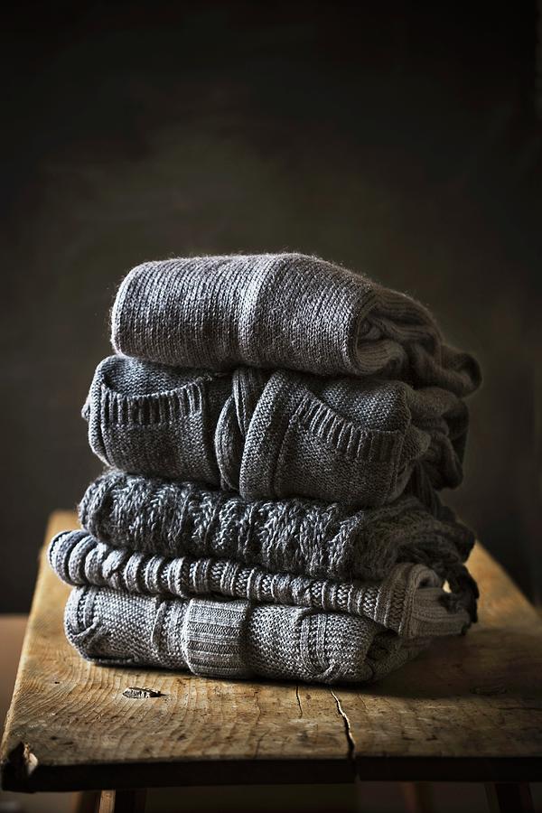 Five Grey Sweaters Stacked On A Wooden Table Photograph by Colin Cooke