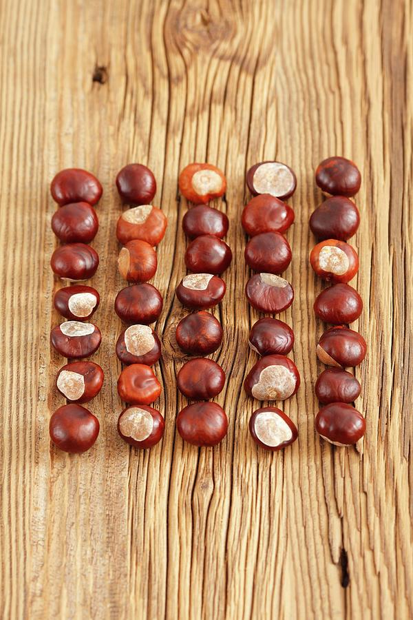 Five Rows Of Conkers On Wooden Surface Photograph by Rua Castilho