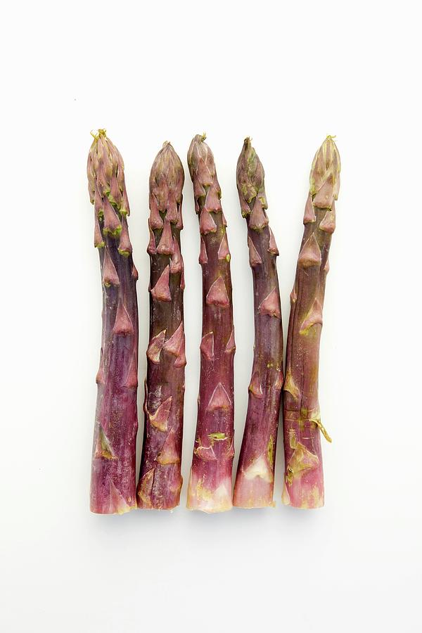 Five Spears Of Purple Asparagus On A White Surface Photograph by William Boch
