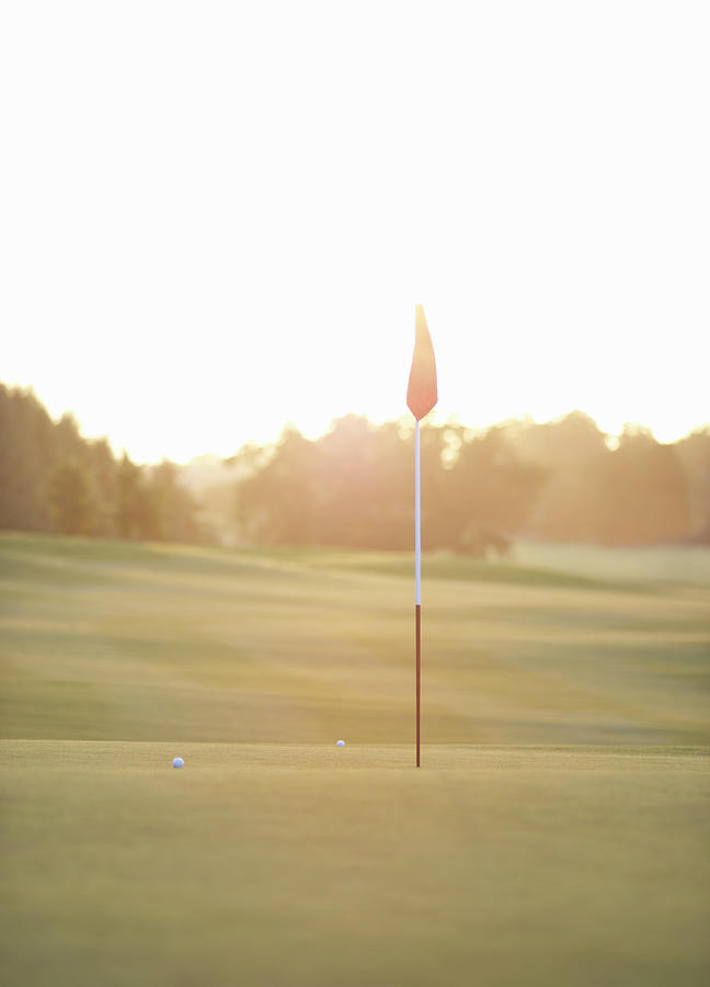 Flag And Golf Balls On Green At Sunset Photograph by Dougal Waters