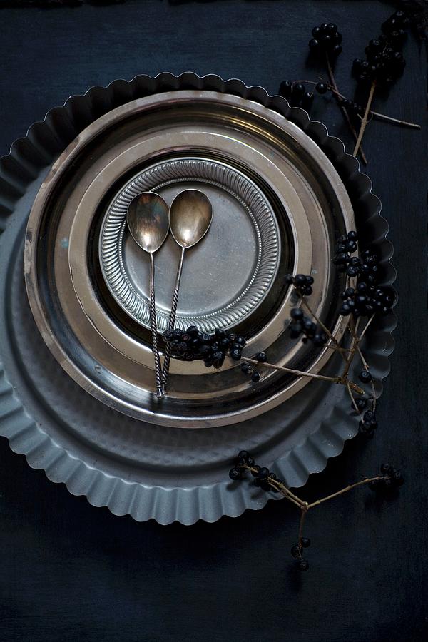 Flan Tin, Metal Plates, Pewter Plates And Silver Spoons On Black Surface Photograph by Alicja Koll
